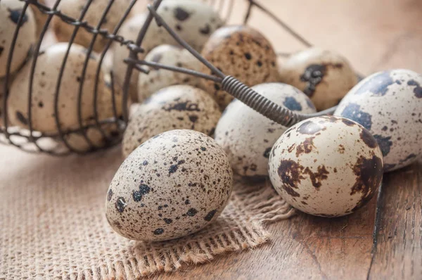 Kwarteleitjes vallen uit metalen korf op houten tafel — Stockfoto