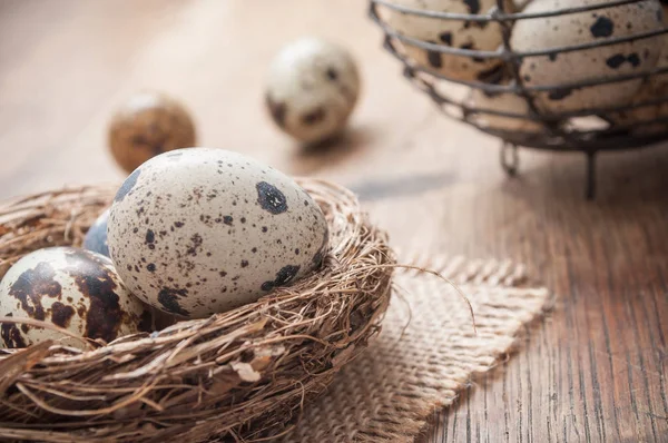 Kwartel eieren in nest op houten tafel met metalen mand — Stockfoto