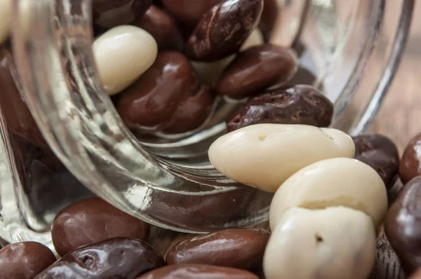 Doces de chocolate caindo de recipiente de vidro — Fotografia de Stock