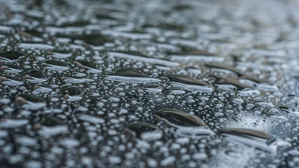 Краплі дощу на чорному автомобілі — стокове фото