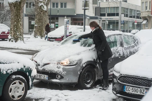 Mujer quita la nieve en su coche en un aparcamiento — Foto de Stock