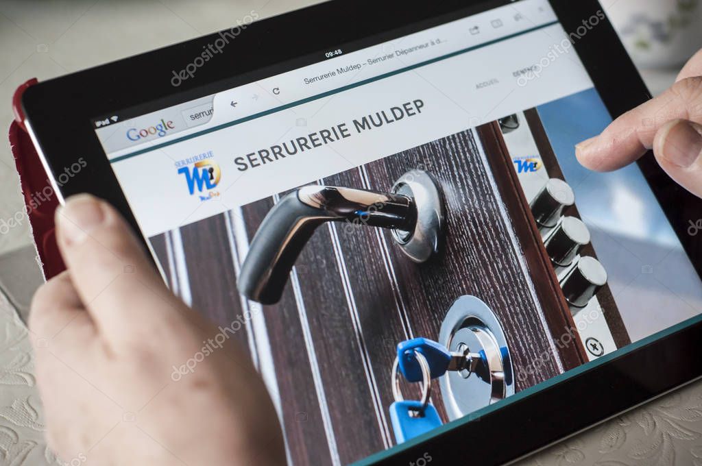 Mulhouse - France - 22 March 2018 - closeup of woman hands on home page of the  locksmith web site on tablet