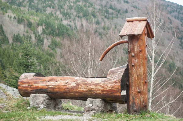 Fonte de madeira típica no fundo da paisagem moutain — Fotografia de Stock