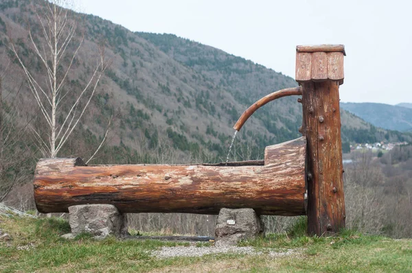 Fuente de madera típica sobre fondo de paisaje de montaña — Foto de Stock