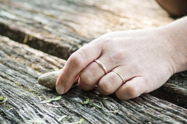 Close-up van de hand van womanwith pebble voor evenwicht op houten tabblad — Stockfoto