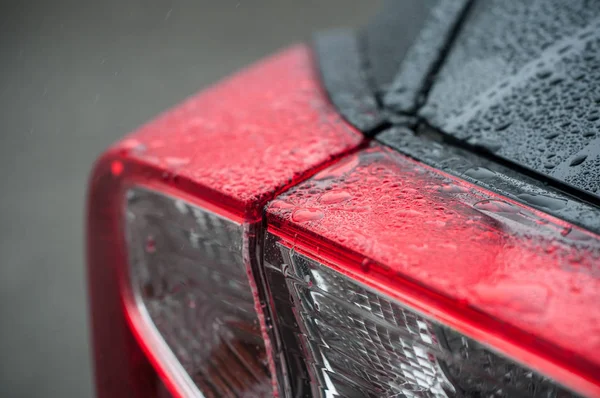 Primer plano de las gotas de lluvia luces traseras de en coche negro — Foto de Stock