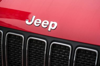 Jeep logo on red car front parked in the street 