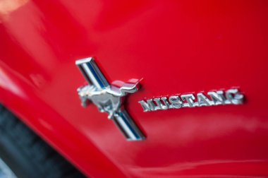 Kırmızı Ford Mustang kapısının üzerindeki logo sokağa park edilmiş. 