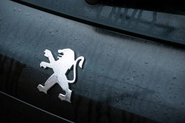 Regen druppels op Peugeot logo op zwarte auto achter geparkeerd in de straat — Stockfoto