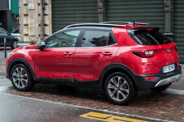 Yağmurlu bir günde sokağa park edilen kırmızı Kia Stonic kavşağının profil görüntüsü