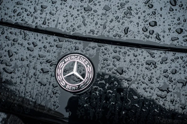 Капли дождя на логотип Мерседес на черной машине, припаркованной на улице — стоковое фото