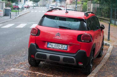 Yağmurlu bir günde caddeye park edilmiş kırmızı Citroen C3 'ün arka görüntüsü