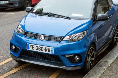 Caddeye park edilmiş mavi Aixam mini arabasının ön görüntüsü.