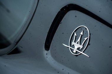 Maserati logo on black sport car parked in the street clipart