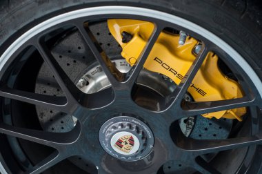 Caddeye park edilmiş Porsche spor arabasının siyah tekerleğinde sarı fren.