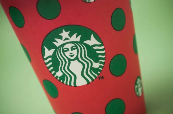 Веселі криштми забирають чашку просто неба з марки Starbucks на зеленому фоні, Starbucks - це знаменита мережа фаст-фуду — стокове фото
