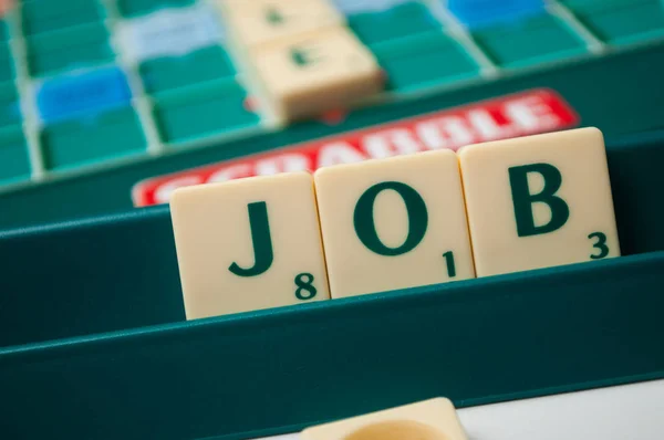 Plastikbuchstaben auf Scrabble-Brettspiel bilden das Wort: Job — Stockfoto