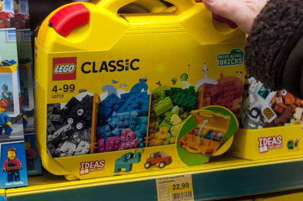 Boîte jaune lego assortiment en main de femme dans un supermarché de jouets — Photo