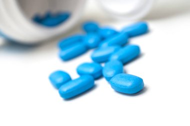 Plastik şişeden beyaz sırt üstü düşen mavi pil kapakları.