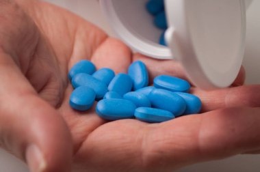 Beyaz arka planda plastik şişeden mavi damlalar düşüyor. 