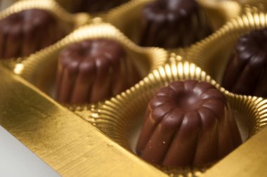 Altın kutuda şekilli kougloflar içinde bir grup çikolata.