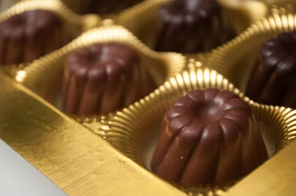 Група шоколадних цукерок у формі баклажанів у золотій коробці — стокове фото