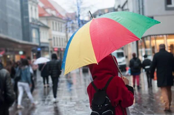 Mulher andando na rua com guarda-chuva arco-íris — Fotografia de Stock