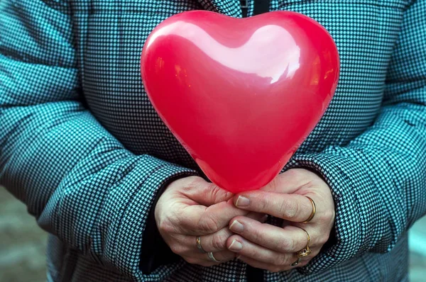 Крупним планом червона надувна куля у формі серця в руках — стокове фото