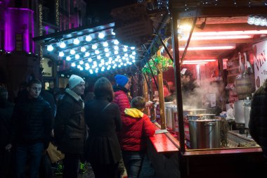 İnsanlar yılbaşı pazarında şarap kulübesinde dikiliyorlar.