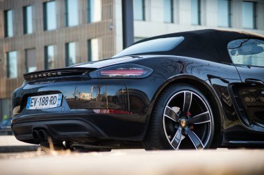 Siyah Porsche 718 'in arka manzarası sokağa park edilmiş.