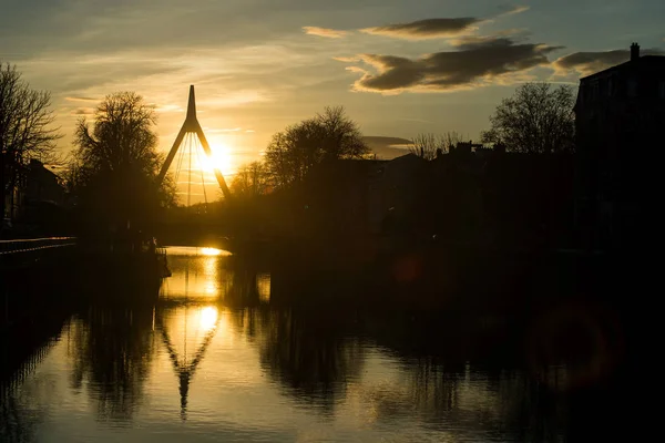 Panorama met silhouet van hangbrug onder het kanaal met reflectie bij zonsondergang — Stockfoto