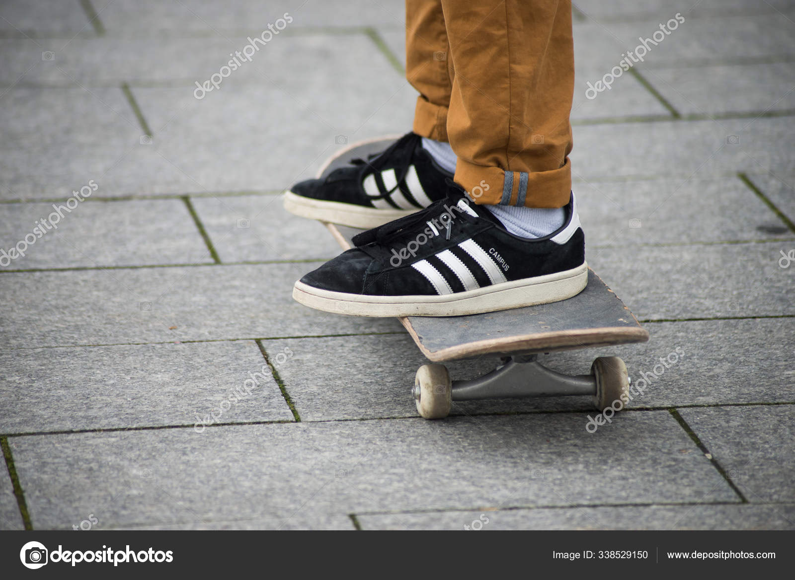 de con zapatillas negras de Adidas de pie sobre tabla skate en la calle — Foto editorial de stock NeydtStock #338529150