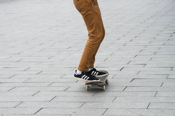 阿迪达斯穿着黑色运动鞋的滑雪者腿在街上滑板上打滚 — 图库照片