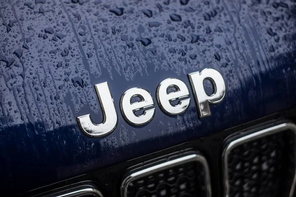 Rain drops on Jeep logo on blue car parked in the street — Stock Photo, Image