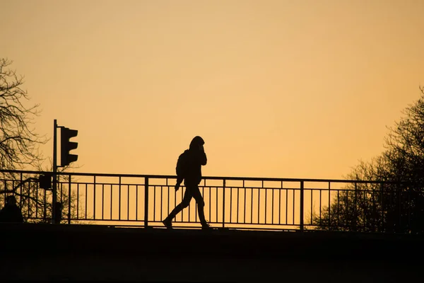 Uitzicht op silhouet van een jonge man die over de brug loopt — Stockfoto