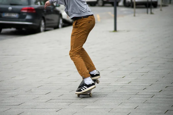 Skater legs wearing black sneakers by Adidas rolling on skate board in the street — Stock Photo, Image