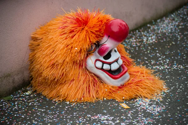 Karnevalsmaske mit orangefarbener Perücke posiert vor dem Karneval auf dem Boden — Stockfoto