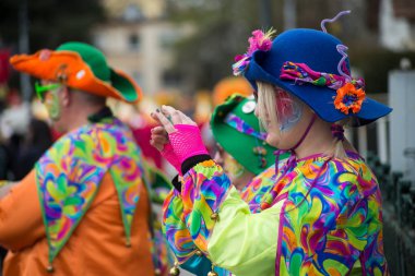 İnsanlar sokakta renkli palyaço kostümüyle fotoğraf çekiyorlar.