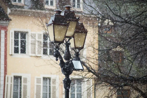 view of retro street lamp with old buildings on background by snowy day