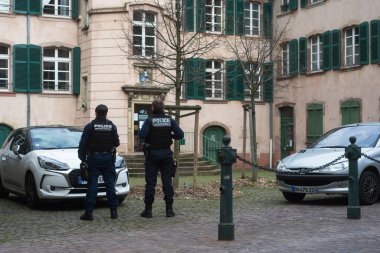 Mulhouse - Fransa - 14 Mart 2020 - Sokaktaki araçları kontrol eden iki belediye polisinin arka plandaki portresi