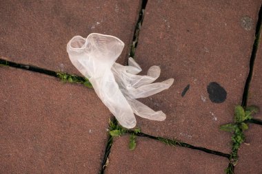 Sokakta bırakılmış kullanılmış lateks eldivenlerin yakın çekimi. 