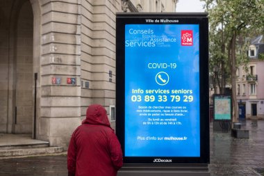 Mulhouse - Fransa - 2 Mayıs 2020 - Coronavirüs salgınına karşı bilgi paneline bakan kadının portresi