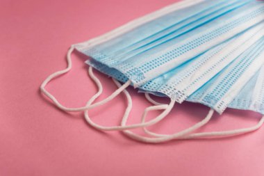 Covid-19 salgınından korunmak için pembe arka planda tıbbi maskelerin yakın plan görüntüleri.