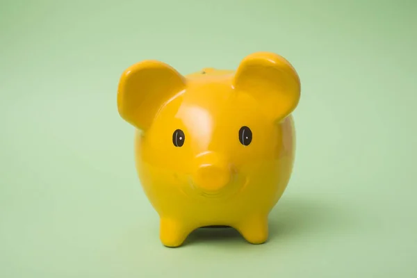 Closeup of yellow piggy bank on green background
