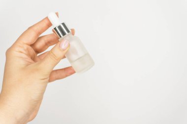 Şeffaf ve Matt şişe serumla ya da cam şişe ve pipetle yağlı. Beyaz arka planda cilt bakım ürünü var. Cam göz damlası şişesi, sağlık ve kişisel bakım..