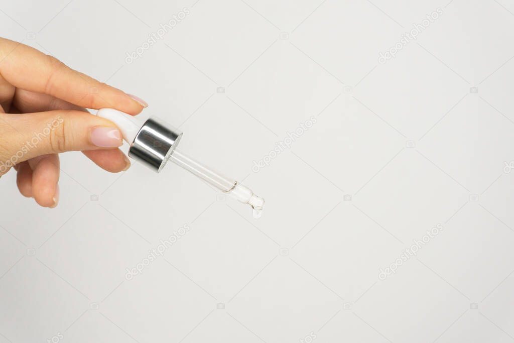 Glass pipette serum or oil essence dropper . Skincare beauty product in hand on the white background. wellness and self care. Natural organic cosmetic. Close-up oil face drop. Copy space.