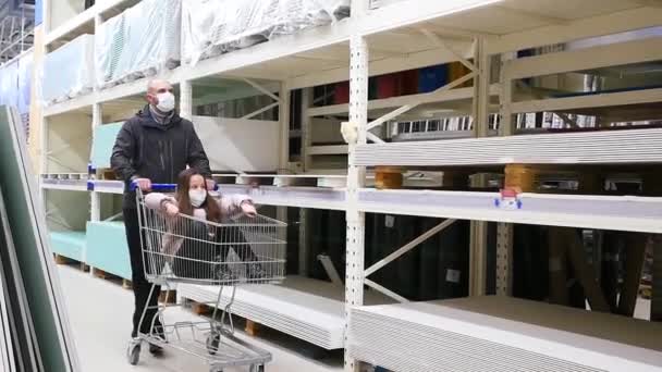 Ve stavebním supermarketu otec vozí svou dceru na vozíku.. — Stock video