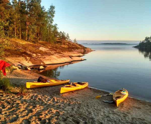 A row of kayaks lying on the beach at the beginning of the day.Canoe rental.lake Ladoga. Karelia. Russia.