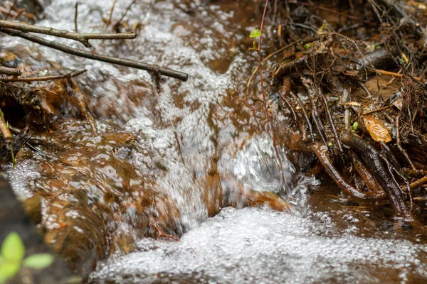 The water source flows down the rocks into the river. Water in the form of bubbles flows down the stones