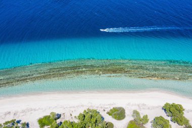 Port Glarokavos 'taki motorlu tekne ve Kassandra penisula Chalkidiki' deki lagün plajlarının insansız hava aracı görüntüsü
